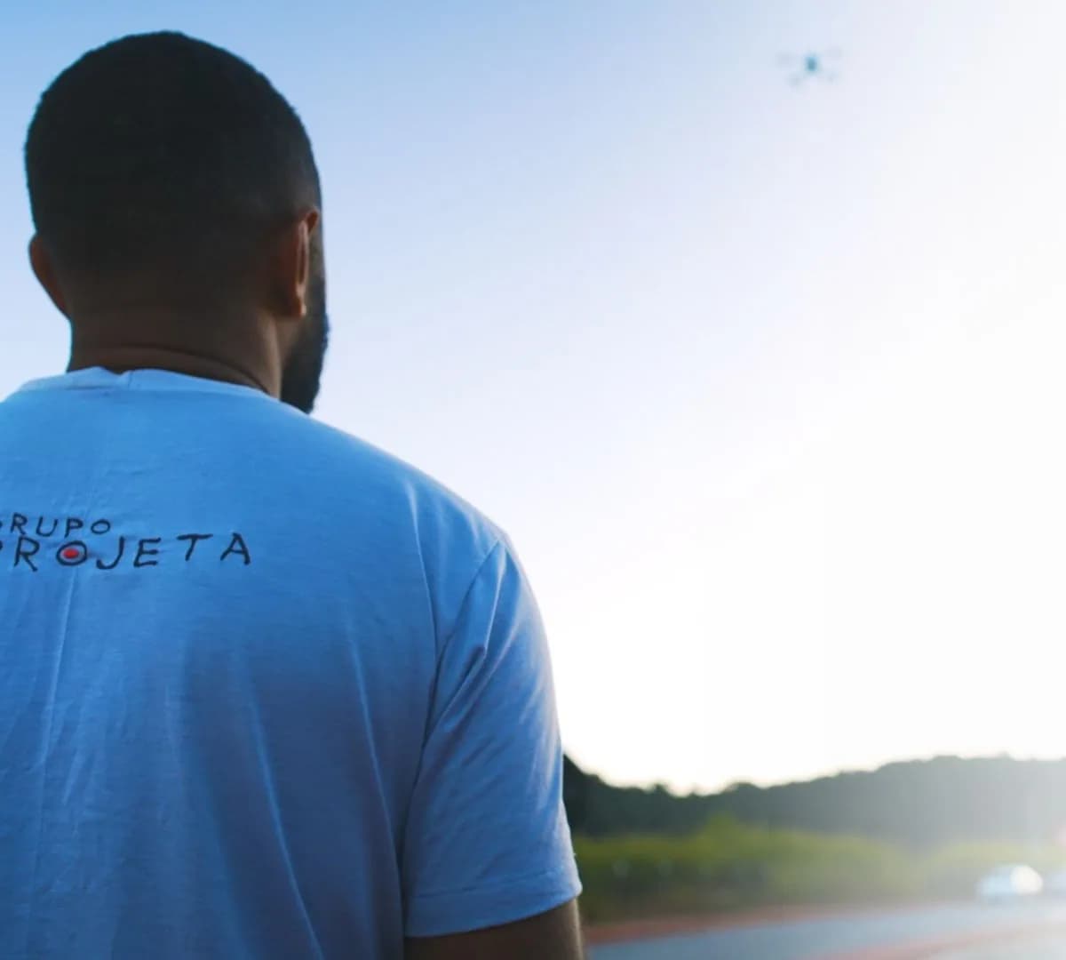 Profissional com camiseta do Grupo Projeta acompanha voo de drone em levantamento às margens de uma rodovia