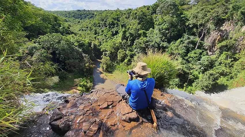 Técnico faz medição em curso d'água entre pedras, em trabalho de campo