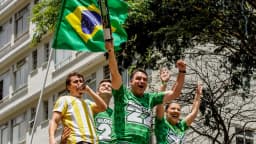 Flávio Bolsonaro ergue bandeira do Brasil ao lado de apoiadores em ato de campanha na Avenida Paulista
