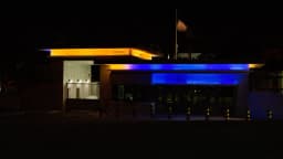 Portaria da Embaixada dos Estados Unidos em Brasília à noite, com a bandeira americana hasteada