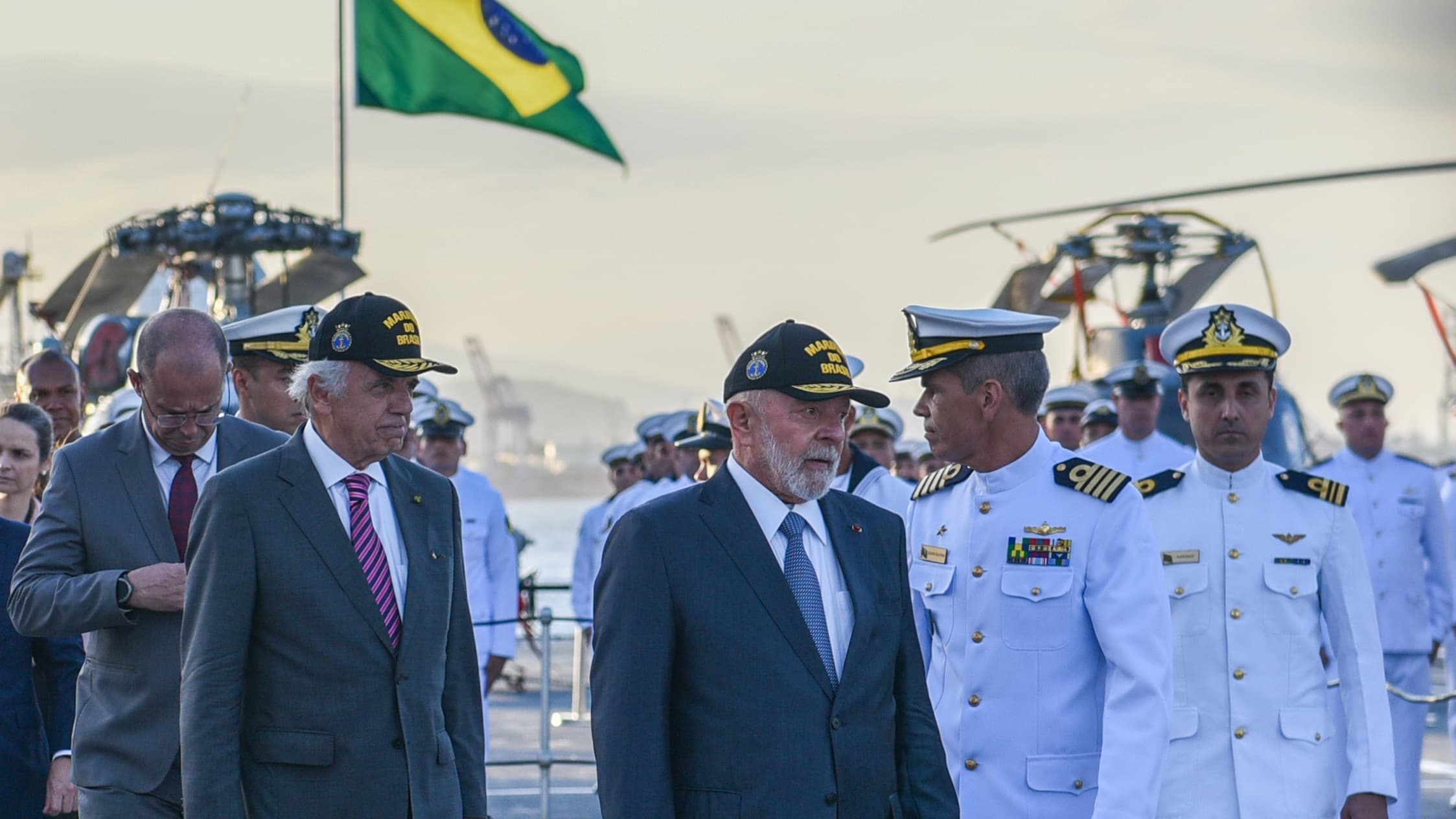 Lula caminha ao lado de autoridades e oficiais da Marinha do Brasil em navio, com bandeira nacional ao fundo (foto de arquivo)