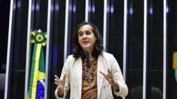 Deputada federal trans discursa no plenário da Câmara dos Deputados, com a bandeira do Brasil ao fundo, em foto de arquivo usada como contexto sobre candidaturas trans