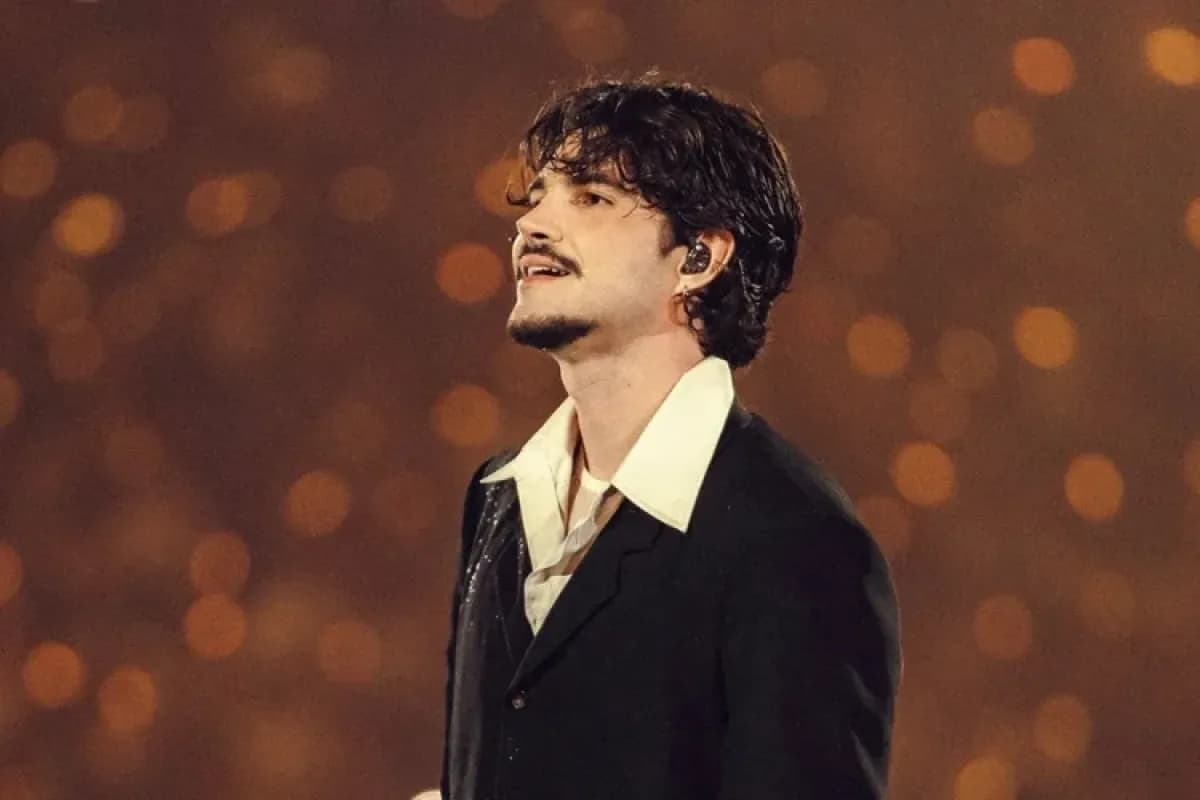 Jão se apresenta em palco durante show, vestindo terno preto com camisa branca