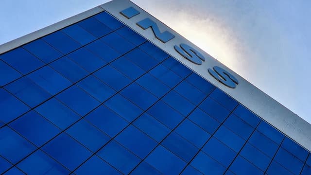 Fachada do prédio-sede do INSS em Brasília, vista de baixo para cima, com o letreiro da instituição contra o céu azul