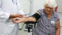 Idosa tem a pressão aferida por profissional de saúde