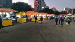Consumidores caminham entre bancas de feira livre à noite em Porto Alegre, imagem de arquivo de comércio de rua no Brasil