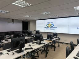 Sala do Gabinete Integrado de Segurança do TRE-MG, em Belo Horizonte, com estações de monitoramento e telão com a logo do gabinete