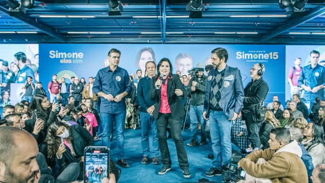 Simone Tebet discursa em lançamento de campanha própria em São Paulo, com banner 'Simone15' ao fundo