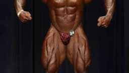 Fisiculturista em pose de competição no palco de evento IFBB (imagem ilustrativa da categoria, não é Keone Pearson nem Lucas Garcia)