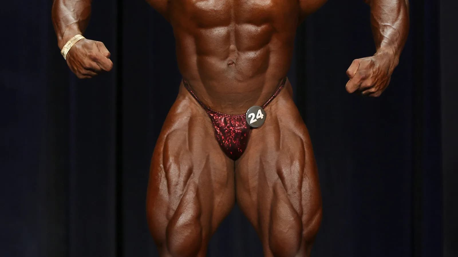 Fisiculturista em pose de competição no palco de evento IFBB (imagem ilustrativa da categoria, não é Keone Pearson nem Lucas Garcia)