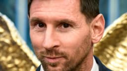 Lionel Messi sorri em evento formal, vestindo terno