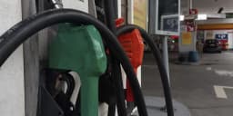 Bicos de bomba de combustível verde e vermelho em posto de gasolina