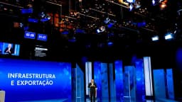 Estúdio do debate presidencial da TV Globo, com telões, cronômetros e um dos candidatos ao fundo