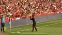 Clarence Seedorf em campo, vestindo uniforme do Milan, durante lance de jogo com torcida ao fundo