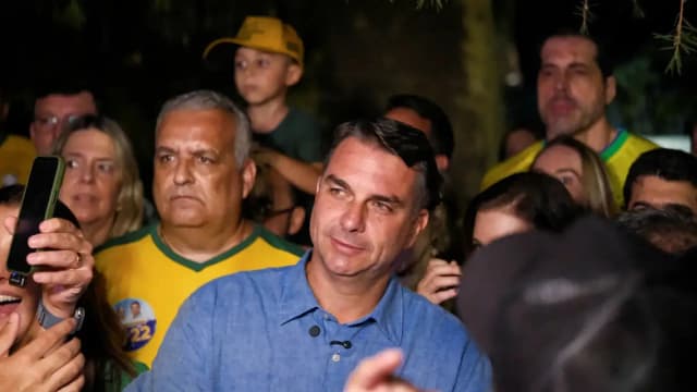 Flávio Bolsonaro cercado de apoiadores durante visita ao pai em prisão domiciliar, em São Paulo