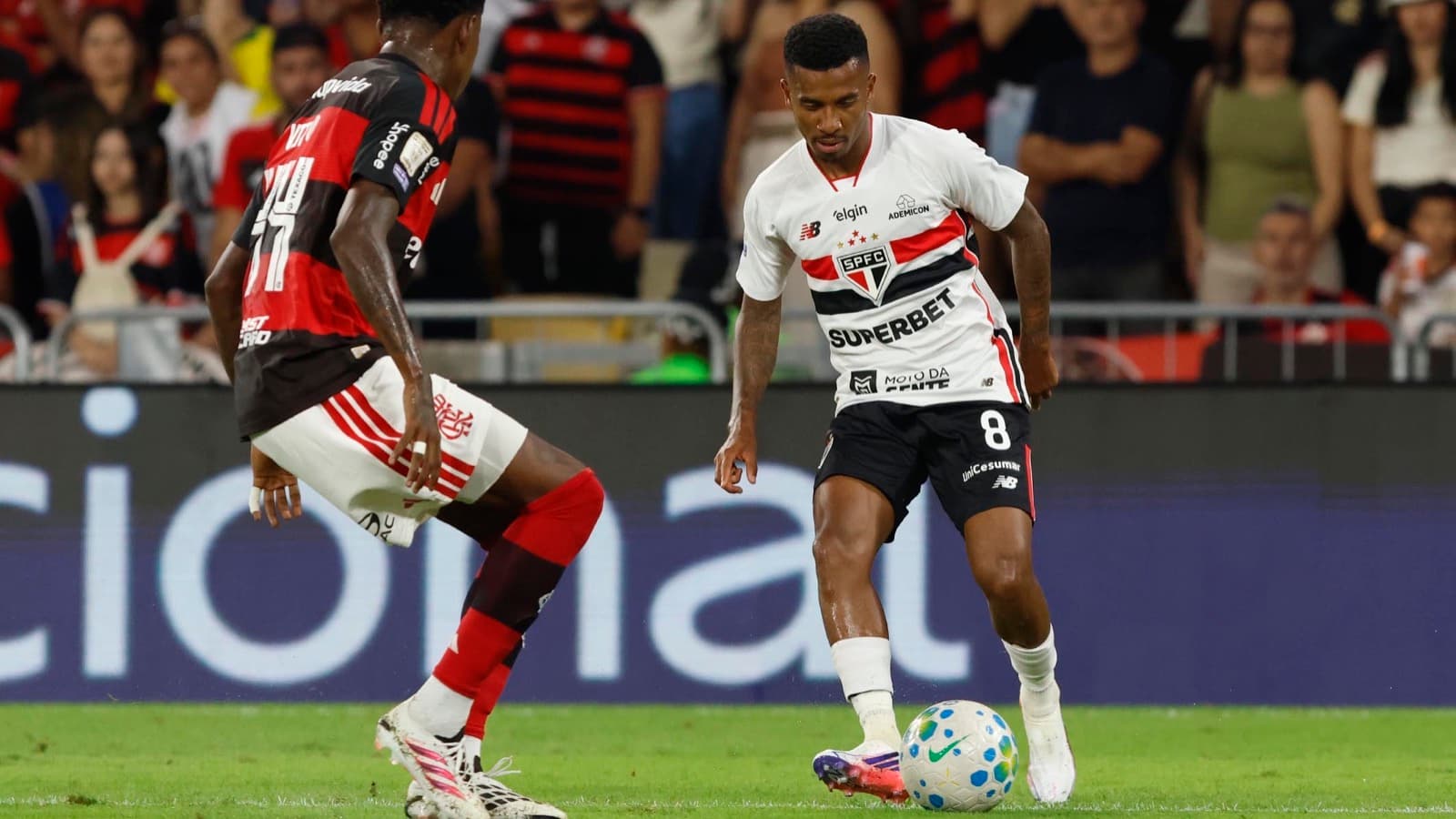 Jogador do São Paulo conduz a bola marcado por jogador do Flamengo durante partida no Maracanã