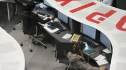 Operadores trabalham entre telas no pregão da Bolsa de Tóquio, com painel do índice Topix ao fundo