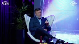 Alessandro Feijó fala com o dedo indicador erguido durante entrevista ao programa Te Conto, Uai, em estúdio com luzes roxas