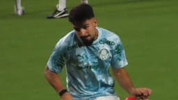 Jogador do Palmeiras com uniforme de treino, chutando a bola em campo