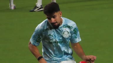 Jogador do Palmeiras com uniforme de treino, chutando a bola em campo