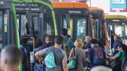 Passageiros embarcam em ônibus lotados em terminal urbano durante o horário de pico