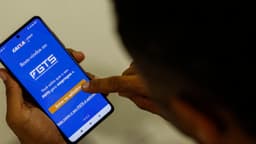Foto de arquivo: pessoa segura celular com a tela inicial do aplicativo FGTS da Caixa aberta e toca o botão de entrar