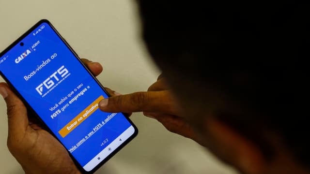 Foto de arquivo: pessoa segura celular com a tela inicial do aplicativo FGTS da Caixa aberta e toca o botão de entrar
