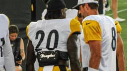 Aaron Rodgers, com boné branco, conversa com um companheiro de equipe durante treino dos Pittsburgh Steelers