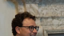 Dario Amodei, executivo-chefe da Anthropic, sorri usando óculos e terno azul-marinho em ambiente formal