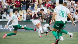 Jogadores disputam a bola em lance de jogo do Brasileirão, com torcida ao fundo