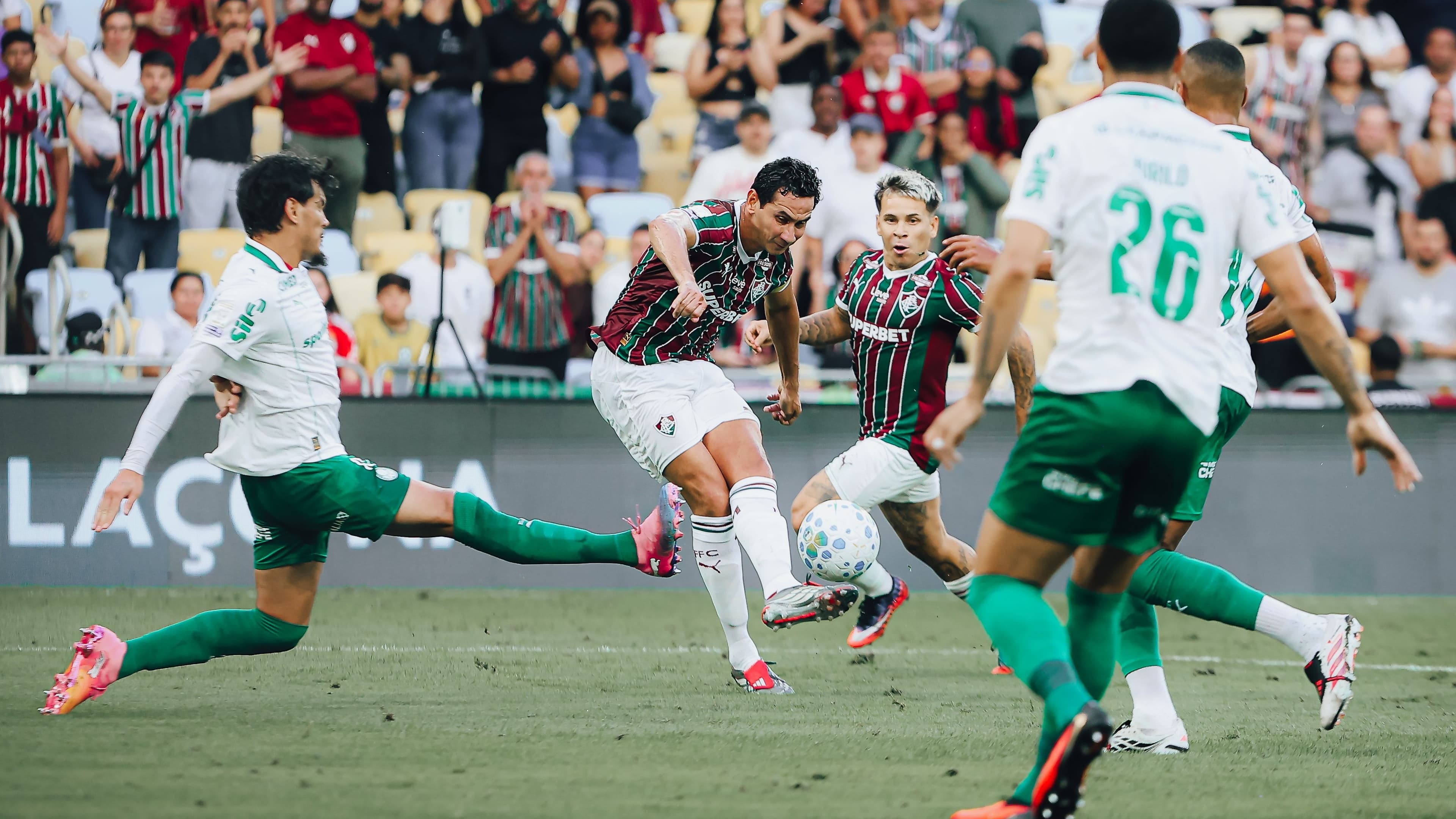 Jogadores disputam a bola em lance de jogo do Brasileirão, com torcida ao fundo