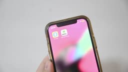 Mão segura celular com o aplicativo e-Título aberto, símbolo das Eleições 2026