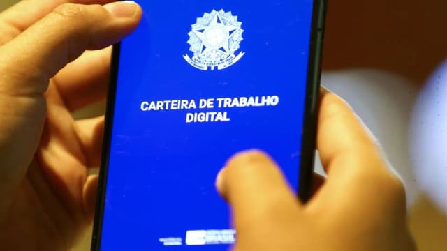 Mão segura celular com a tela do aplicativo Carteira de Trabalho Digital