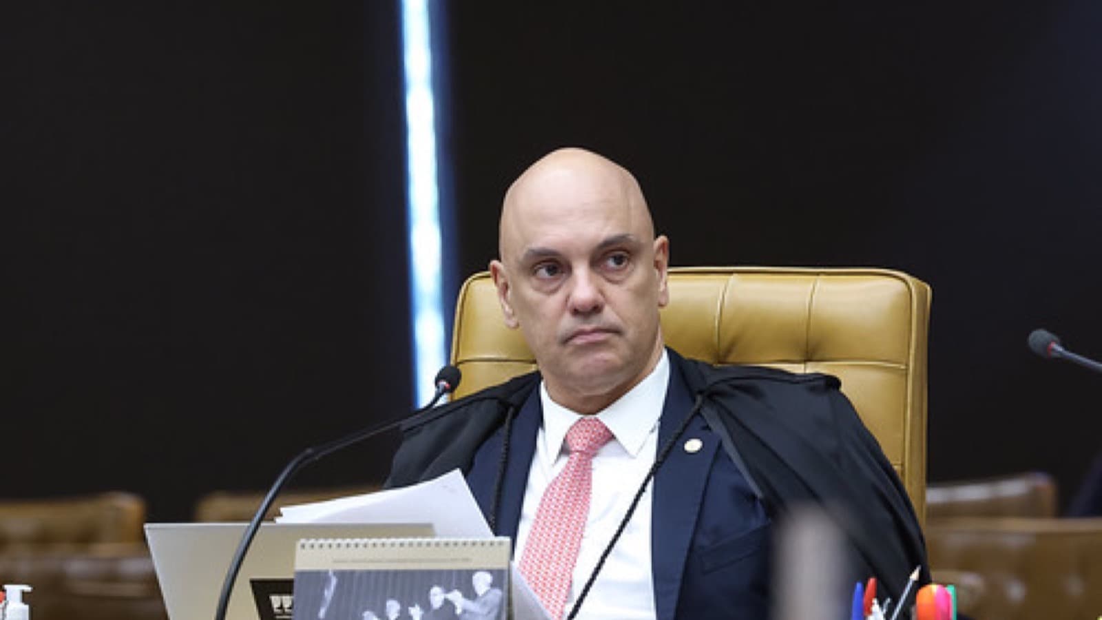 O ministro do STF Alexandre de Moraes durante sessão plenária, sentado em sua cadeira, com toga e microfone à frente