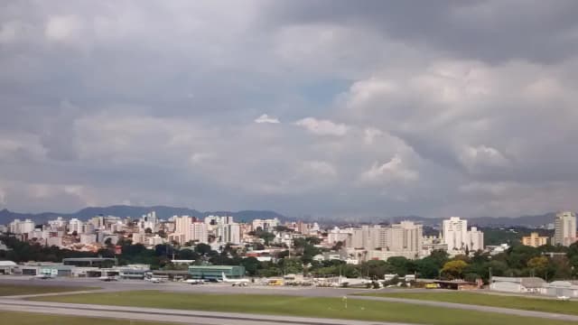 Vista aérea da pista do Aeroporto da Pampulha com a cidade de Belo Horizonte ao fundo