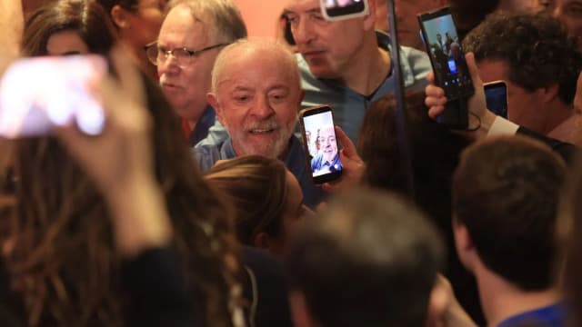 Lula sorri cercado de apoiadores que fotografam com celulares