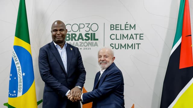 Daniel Chapo aperta a mão de Lula em reunião bilateral, com as bandeiras do Brasil e de Moçambique ao fundo