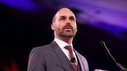 Eduardo Bolsonaro discursa em evento nos Estados Unidos, de terno cinza e gravata bordô