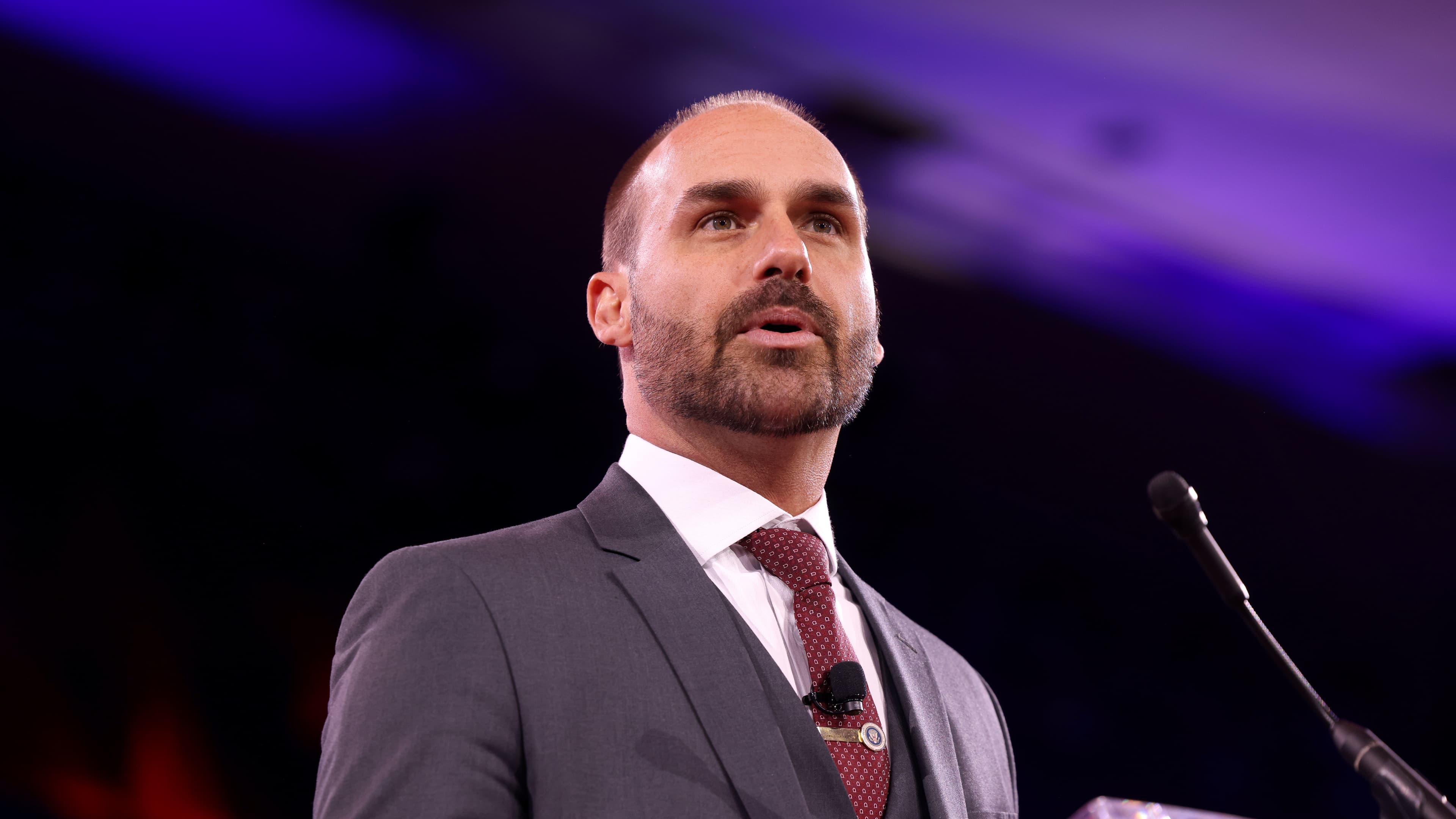 Eduardo Bolsonaro discursa em evento nos Estados Unidos, de terno cinza e gravata bordô