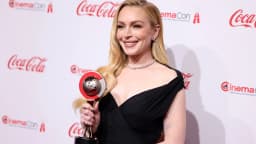 Lindsay Lohan sorri em tapete vermelho, usando vestido preto, em evento recente