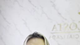 Advogada Isabela Costa fala sobre controle de celular em relacionamentos durante vídeo, com fundo de mármore e símbolo da balança da Justiça