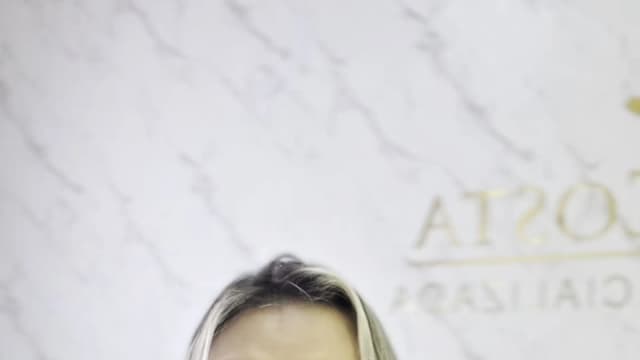 Advogada Isabela Costa fala sobre controle de celular em relacionamentos durante vídeo, com fundo de mármore e símbolo da balança da Justiça