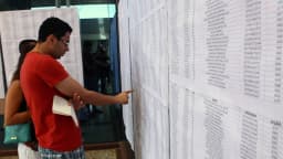 Eleitores conferem lista de candidatos em painel afixado em seção eleitoral