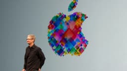 Tim Cook, CEO da Apple, ao lado do logo colorido da empresa