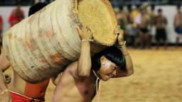 Homens indígenas carregam tora de madeira durante competição tradicional