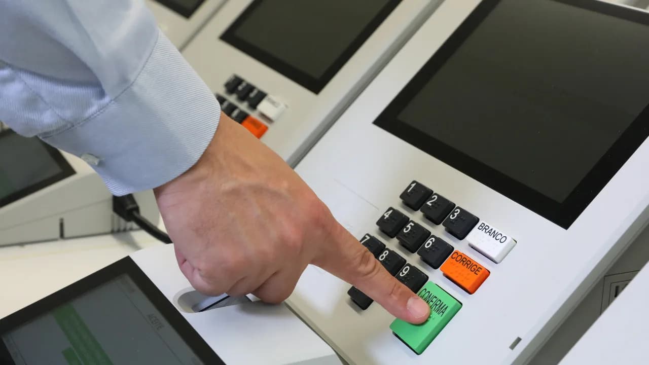 Mão de eleitor digita número de candidato em urna eletrônica