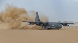 Avião HC-130J Combat King II da Força Aérea dos Estados Unidos decolando em meio a nuvem de poeira