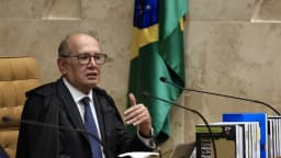 Ministro Gilmar Mendes fala durante sessão plenária do STF, vestindo toga, com a bancada e a bandeira do Brasil ao fundo