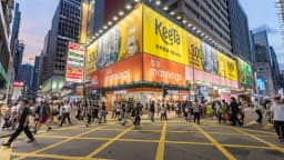 Painel publicitário da Keeta em uma rua de Hong Kong, com pedestres passando