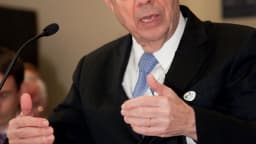 Henrique Meirelles discursa gesticulando durante evento, com papéis na mão